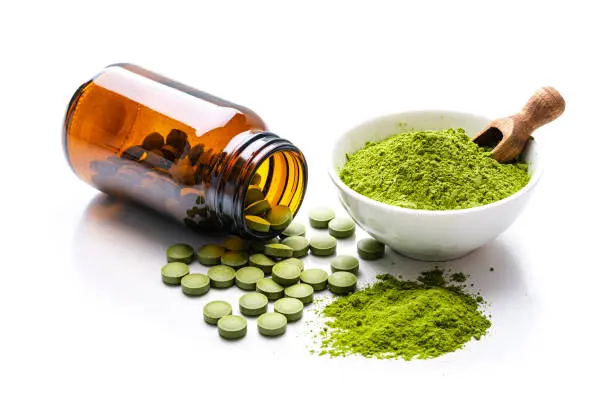 Moringa powder and pills on white background.webp
